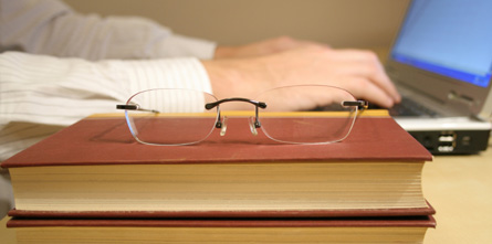 Close up of books with reading glasses on top